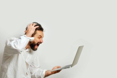 Adam kafasını tutuyor ve beyaz bir arka planda izole edilmiş bir laptop ekranına umutsuzca bakıyor. Duygular ve finansal kriz kavramı.