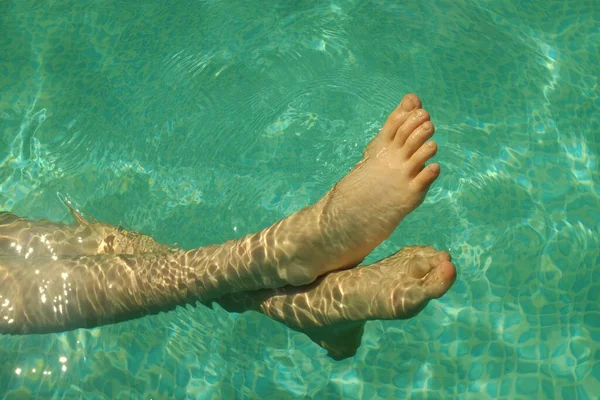 Childs pies en el agua azul transparente de la piscina. — Foto de Stock