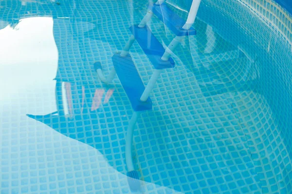 Agua azul y escalera para descender a la piscina del marco. El reflejo del techo de una casa de campo es visible en el agua. — Foto de Stock