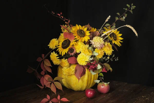 Bloemenarrangement met zonnebloemen in een pompoen op een houten tafel op een zwarte achtergrond. Thanksgiving en kopieer ruimte concept — Stockfoto