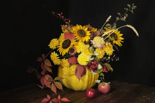 Balkabağında ayçiçekleri olan bir çiçek aranjmanı. Siyah arka planda, ahşap bir masada. Şükran Günü ve fotokopi alanı