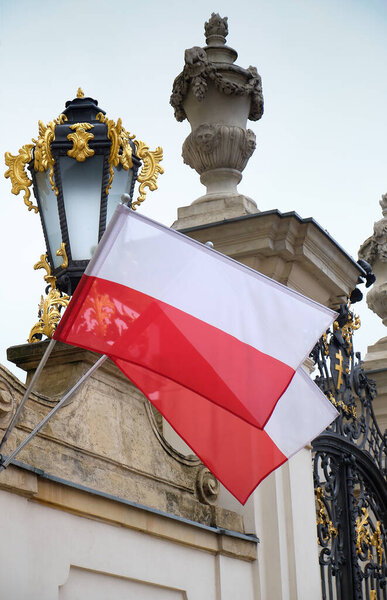 Варшава, Польша, 14 сентября 2025 года. Флаг Польши, развевающийся на фасаде Потоцкого дворца в Варшаве, обрамлен богато украшенным фонарем и классической архитектурой.