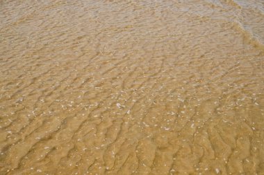 Doğal dalga dokusuna sahip deniz kumu ve küçük köpük kabarcıkları, yakın plan soyut arka plan. Tasarım, duvar kağıdı ya da ekolojik kavramlar için minimalist plaj deseni, sakin güneşli bir gün. Yukarıdan görünüm. 