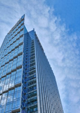 Çağdaş cam gökdelenler bulutları ve gökyüzünü yansıtıyor, şehir mimarisini ve modern şehir tasarımını gözler önüne seriyor. Resmin ortasında kopyalama alanı var. Dikey fotoğraf. Varşova, Polonya