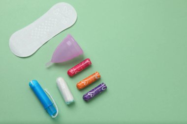 Kadınsı pedler, tamponlar, regl kupası yeşil arka planda dişi hijyen ürünleri