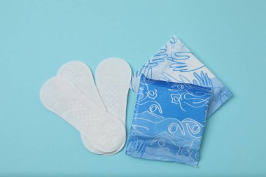 Kadınsı pedler, tamponlar, adet kupası mavi arka planda dişi hijyen ürünleri.