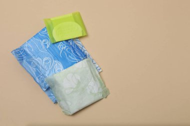 Kadın pedleri, tamponlar, regl kupası bej arka planda kadın hijyen ürünleri.