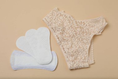 Kadın pedleri, tamponlar, regl kupası bej arka planda kadın hijyen ürünleri.