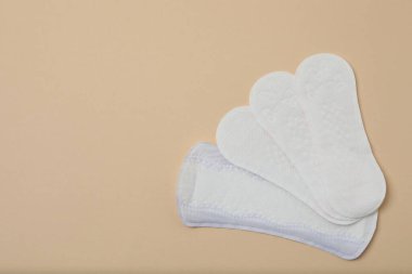 Kadın pedleri, tamponlar, regl kupası bej arka planda kadın hijyen ürünleri.