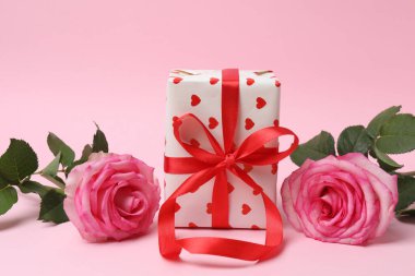 Pembe arkaplanda pembe güller ve hediye kutusu