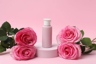 Pembe güller, pembe arka planda kozmetik kavanozlar.