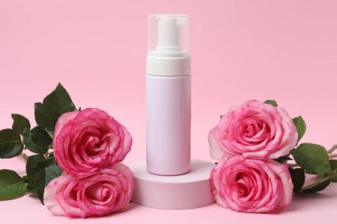 Pembe güller, pembe arka planda kozmetik kavanozlar.