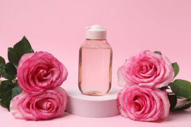Pembe güller, pembe arka planda kozmetik kavanozlar.