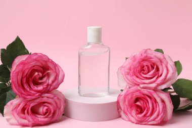 Pembe güller, pembe arka planda kozmetik kavanozlar.