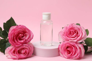 Pembe güller, pembe arka planda kozmetik kavanozlar.