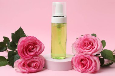 Pembe güller, pembe arka planda kozmetik kavanozlar.