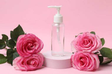 Pembe güller, pembe arka planda kozmetik kavanozlar.