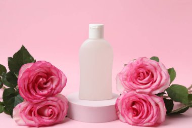 Pembe güller, pembe arka planda kozmetik kavanozlar.