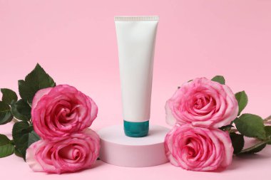 Pembe güller, pembe arka planda kozmetik kavanozlar.