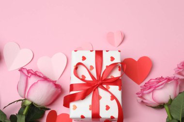 Pembe arkaplanda pembe güller ve hediye kutusu