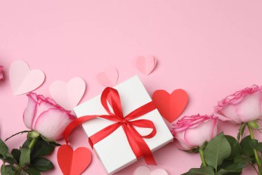 Pembe arkaplanda pembe güller ve hediye kutusu