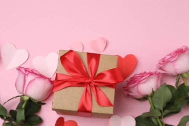 Pembe arkaplanda pembe güller ve hediye kutusu