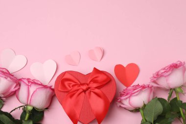 Pembe arkaplanda pembe güller ve hediye kutusu