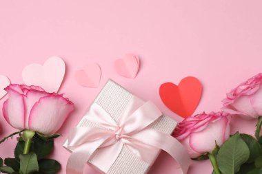 Pembe arkaplanda pembe güller ve hediye kutusu