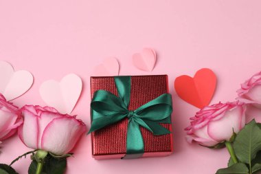 Pembe arkaplanda pembe güller ve hediye kutusu