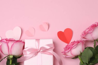 Pembe arkaplanda pembe güller ve hediye kutusu