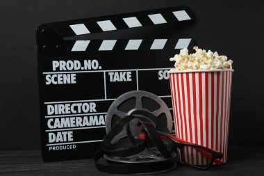 Lezzetli, yumuşak patlamış mısırla dolu, siyah arka planda 3 boyutlu gözlüklü klasik kırmızı ve beyaz çizgili kutu..