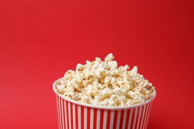 Klasik kırmızı ve beyaz çizgili kutu. Lezzetli, yumuşak patlamış mısır dolu. Kırmızı arka planda 3 boyutlu gözlük..