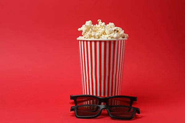 Klasik kırmızı ve beyaz çizgili kutu. Lezzetli, yumuşak patlamış mısır dolu. Kırmızı arka planda 3 boyutlu gözlük..