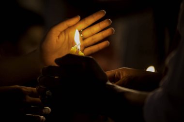 Sarı renkte parlayan ve rüzgarın esmesini engelleyen bir tutunan mum ve resmin sesi var..