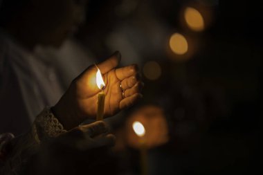 Sarı renkte parlayan ve rüzgarın esmesini engelleyen bir tutunan mum ve resmin sesi var..