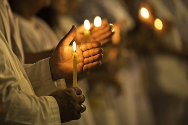 Sarı renkte parlayan ve rüzgarın esmesini engelleyen bir tutunan mum ve resmin sesi var..