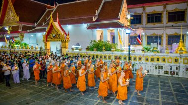 Keşişler ve acemiler, tapınağın etrafındaki mum yakma törenine katılırlar. Budizm 'in önemli gününde 5 Temmuz 2020' de Bangkok, Tayland 'da.