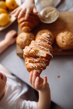 Kruvasanlar, susam tohumlu çörekler, ceviz ve limonlar tahtanın üzerinde..