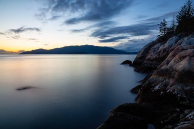 Güzel uzun pozlama manzaralı kayalık kıyı canlı bir bulutlu gün batımı sırasında. Deniz feneri Park, Horseshoe Bay, Vancouver, Bc, Kanada içinde alınan.