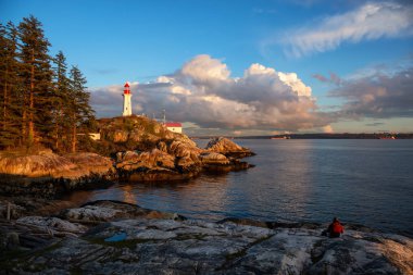 Bir bulutlu gün batımı sırasında kayalık bir kıyısında güzel görünümü bir deniz feneri. Horseshoe Bay, Batı Vancouver, British Columbia, Kanada alınan.