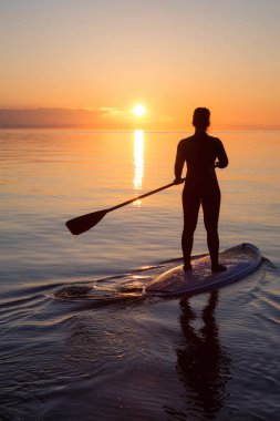 Maceracı bir kürek gemide paddeling bir parlak ve canlı gün batımı sırasında kızdır. Alınan İspanyolca bankalar, Vancouver, British Columbia, Kanada.