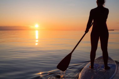 Maceracı bir kürek gemide paddeling bir parlak ve canlı gün batımı sırasında kızdır. Alınan İspanyolca bankalar, Vancouver, British Columbia, Kanada.