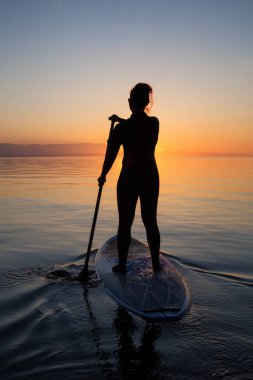 Maceracı bir kürek gemide paddeling bir parlak ve canlı gün batımı sırasında kızdır. Alınan İspanyolca bankalar, Vancouver, British Columbia, Kanada.