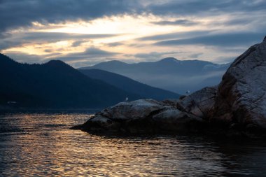 Rocky island with birds during a striking and beautiful sunset. Taken in Howe Sound, North of Vancouver, British Columbia, Canada. clipart