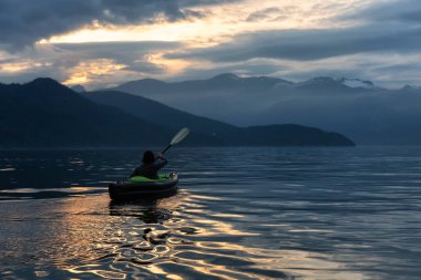 Maceracı kadın Kanada dağ manzarası ile çevrili bir canlı gün batımı sırasında kayak. Vancouver, Bc, Kanada kuzeyindeki Howe ses alınan.