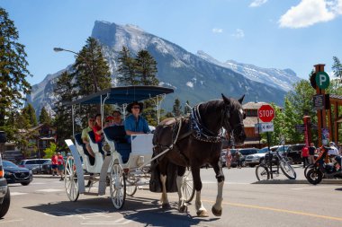 Banff, Alberta, Canada - June 20, 2018: Tourists are taking a tour on a hourse around the city. clipart