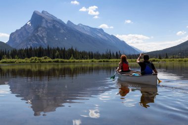 Kaç maceracı arkadaşlar Kanada dağlarla çevrili bir gölde Kano. Alınan Vermilion göllerde, Banff, İngiltere.