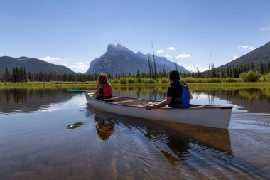Kaç maceracı arkadaşlar Kanada dağlarla çevrili bir gölde Kano. Alınan Vermilion göllerde, Banff, İngiltere.