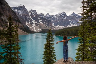Maceracı kadınla silah güzel Kanada Kayalık Dağları ve buzultaş Gölü bakan sarp bir kayalığın kenarına açın. Banff National Park, Alberta, Kanada içinde alınan.