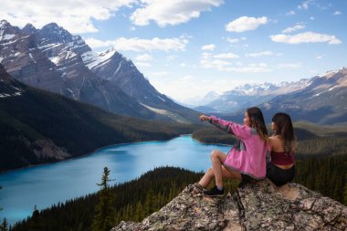 Kanada Kayalık Dağları ve Peyto göl güzel bakan sarp bir kayalığın kenarında oturan maceracı arkadaşlar. Banff National Park, Alberta, Kanada içinde alınan.